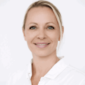 Kvinne smilende helsepersonell i hvit frakk, nærbilde.