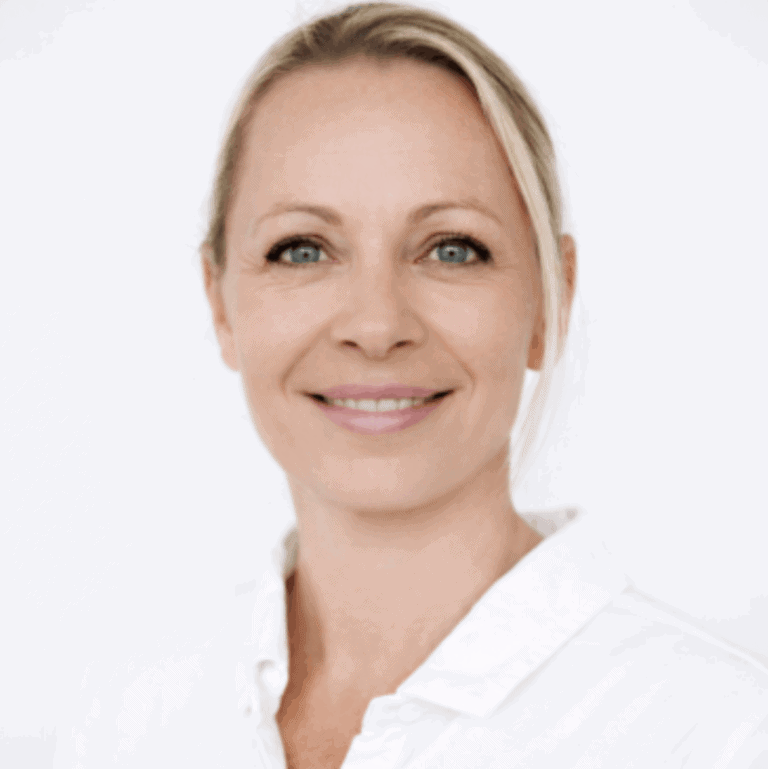 Kvinne smilende helsepersonell i hvit frakk, nærbilde.