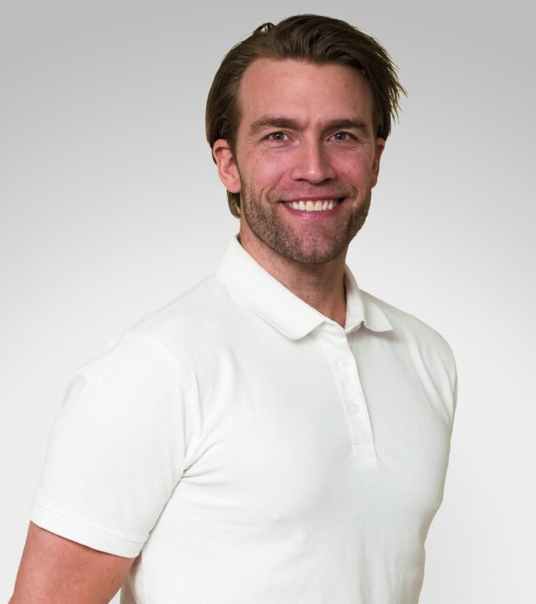 Mann med hvit polo smilende mot kamera, portrett.