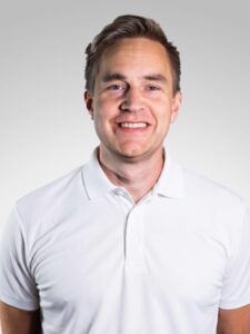 Kiropraktor Ole Jakob Nielsen smiler i hvit skjorte mot en lys bakgrunn.