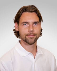 Mann med hvit skjorte ser direkte inn i kamera, portrettbilde.