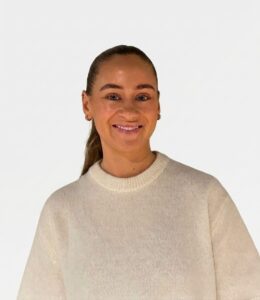 Kvinne smilende, kledd i lys genser, mot hvit bakgrunn.
