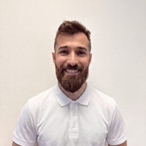 Portrett av Salar Alhussein med smilende ansikt, hvit skjorte, kort hår og skjegg.