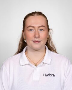 Kvinne i hvit Limba uniform smilende mot kamera.
