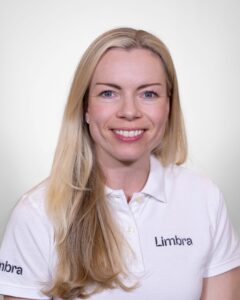 Kvinne i hvit Limba t-skjorte smilende mot kamera.