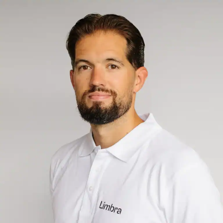 Simen Vedvik, kiropraktor i Limbra, smilende og kledd i hvit klinikkuniform.