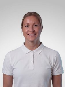 Limbra kiropraktor Stine Enger smilende i hvit polo, portrettfoto.