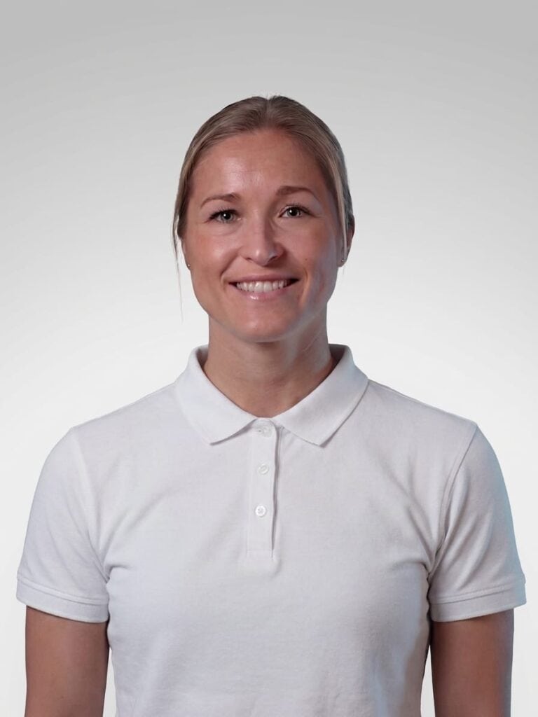 Limbra kiropraktor Stine Enger smilende i hvit polo, portrettfoto.