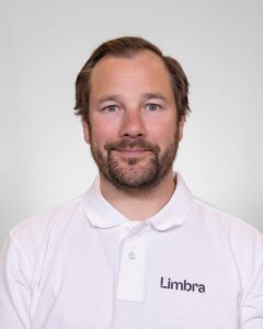 Kiropraktor fra Limbra smilende i hvit skjorte med Limbra-logo.