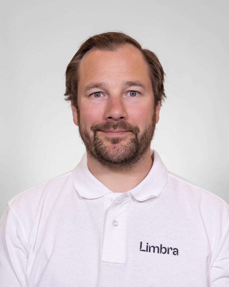 Kiropraktor fra Limbra smilende i hvit skjorte med Limbra-logo.