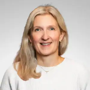 Kvinne med blondt hår smiler mot kameraet.