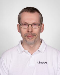 Kiropraktor med Limbra-logo, smilende mann i hvit skjorte.