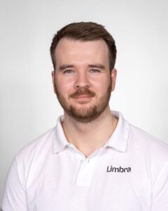 Kiropraktor i hvit Limbra-polo smilende mot kamera.