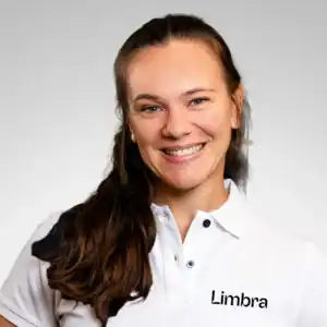 Kvinne med langt brunt hår smiler, iført Limbra uniform.