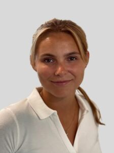 Kvinne med blondt hår i hvit skjorte smilende mot kamera.