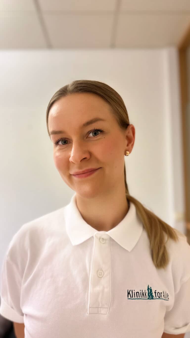 Kvinne i hvit polo med Limbra-logo, smilende, innendørs.