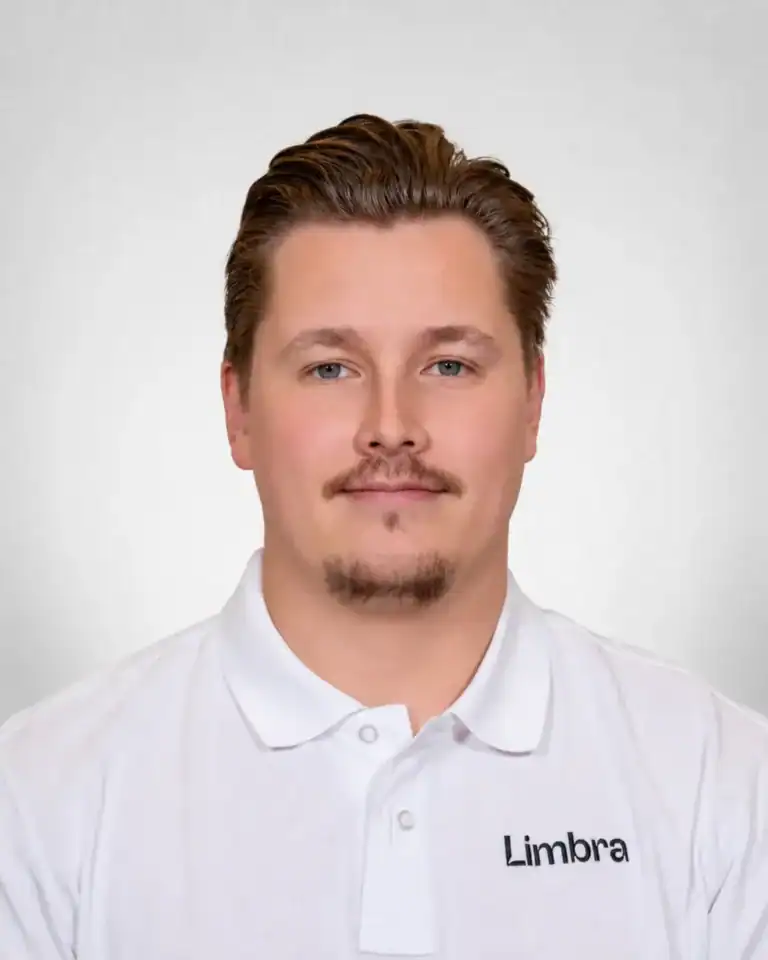 Kvinne i hvit Limbraklær med logo, smilende mot kamera.