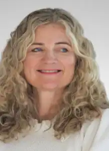 Kvinne med krøllete blondt hår smiler mot kamera.