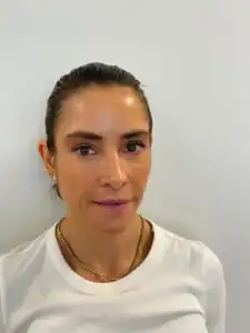 Kvinne med mørkt hår og smil, ser direkte i kameraet.