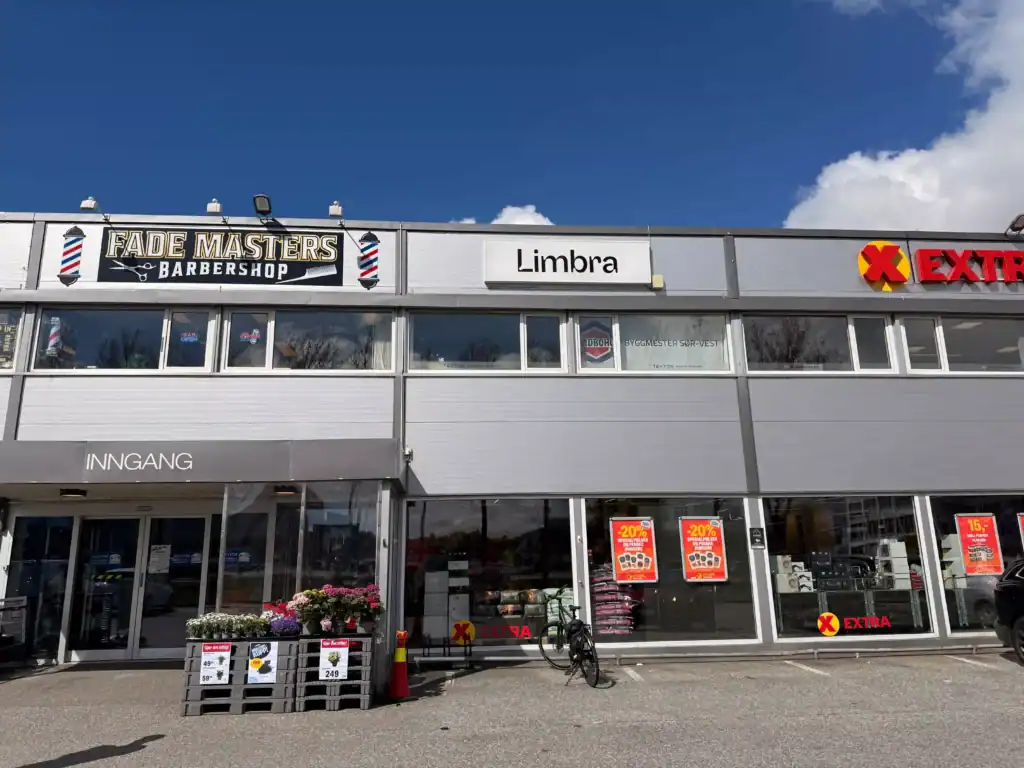 Utsikt over Limbras butikkfront med barberbutikk og Extra supermarked.