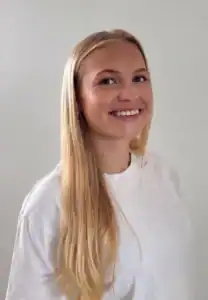 Ung kvinne med langt blondt hår smiler mot kamera.