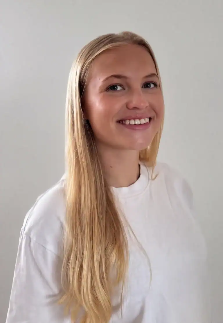 Ung kvinne med langt blondt hår smiler mot kamera.