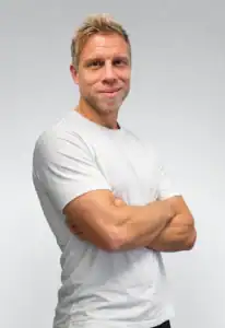 Mann med armkors smilende mot kamera.