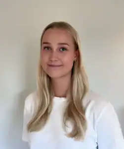 Portrett av en smilende kvinne med langt blondt hår og hvit t-skjorte.