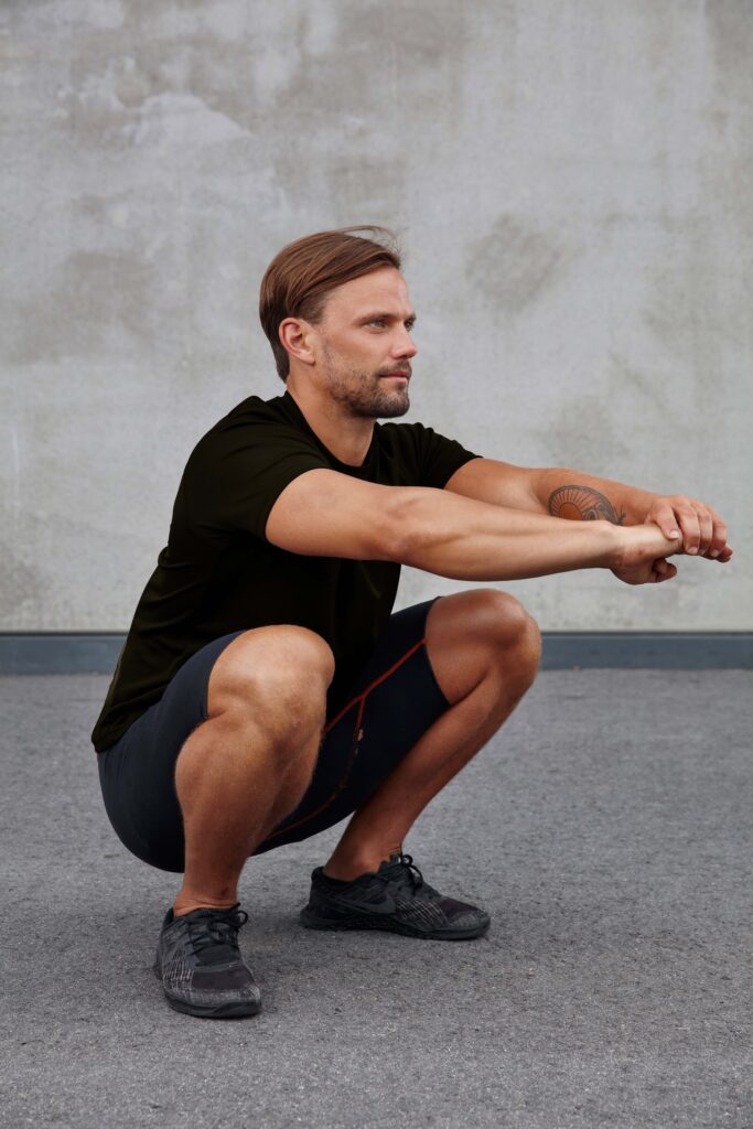 Man performing squat stretch for leg and core strength.