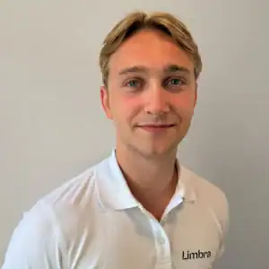 Ung mann i hvit Limbrapolo med smil, mot en lys bakgrunn.