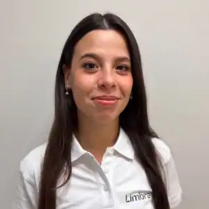 Kvinne med mørkt hår og smilende uttrykk, iført hvit skjorte med Limbra-logo.